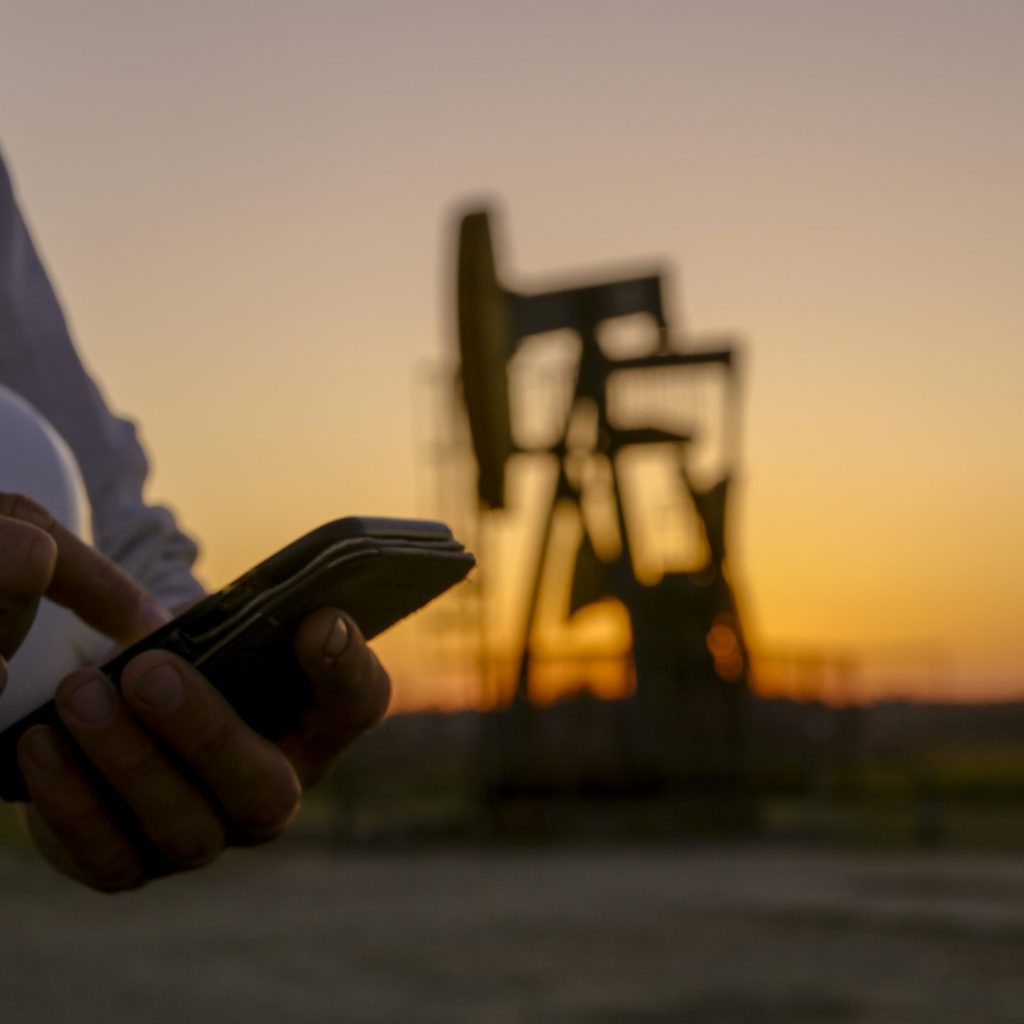 Close up of smart phone against pumpjack