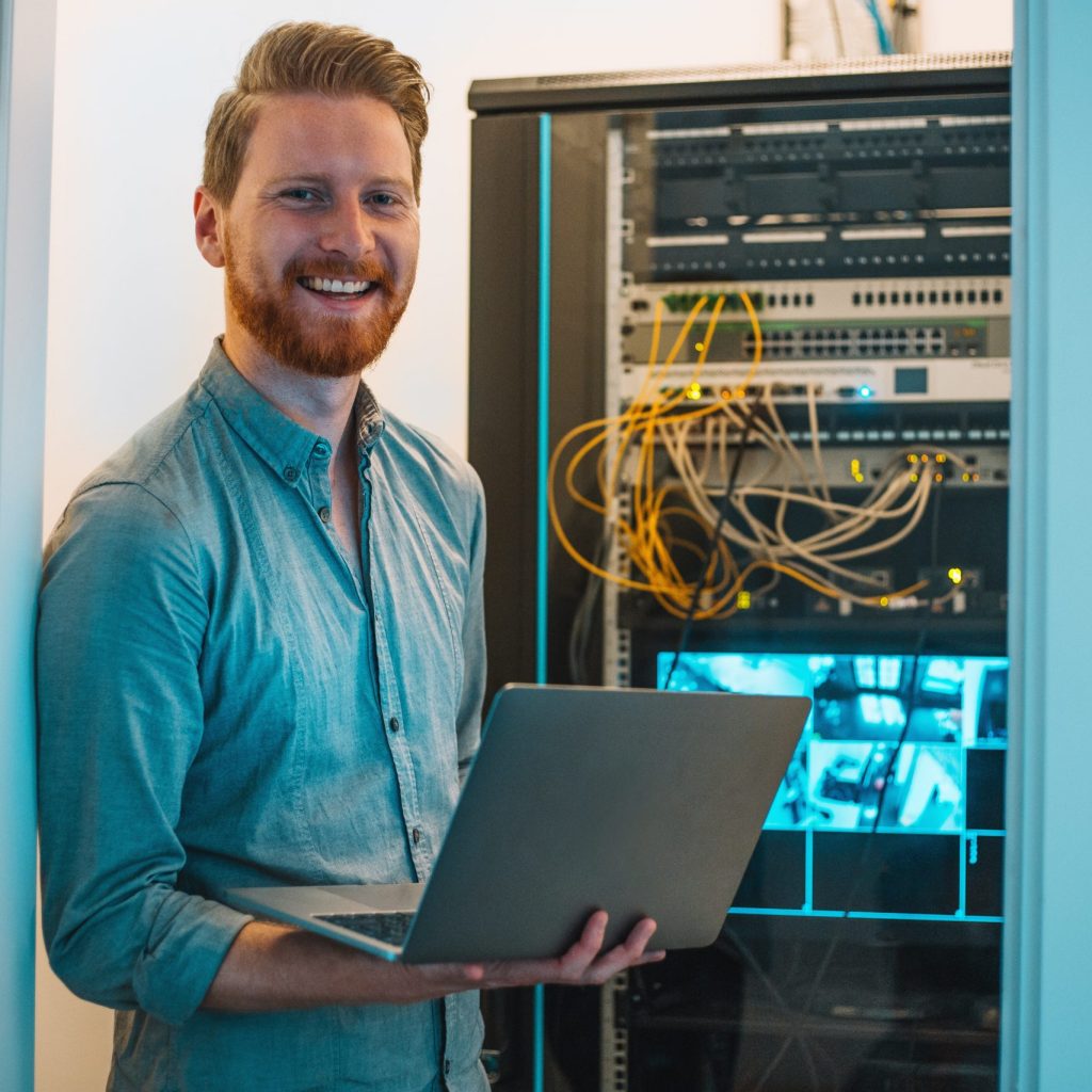 Male Caucasian IT technician using laptop in server room