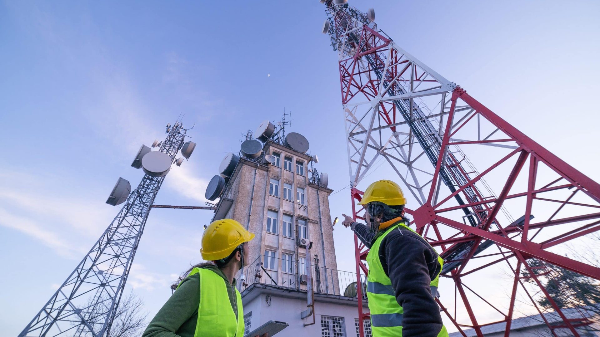 Engineers working on the field near a city Telecomunications tower, checking the condition of the Equipement. Technology and Global Business.