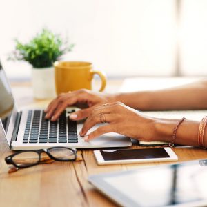 Cropped shot of an unrecognizable businesswoman sitting alone and typing on her laptop during the day at home