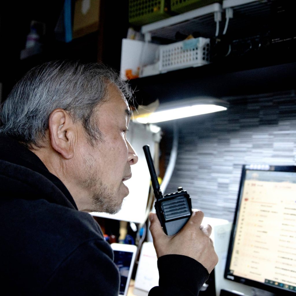 A man giving instructions by radio while looking at a personal computer screen