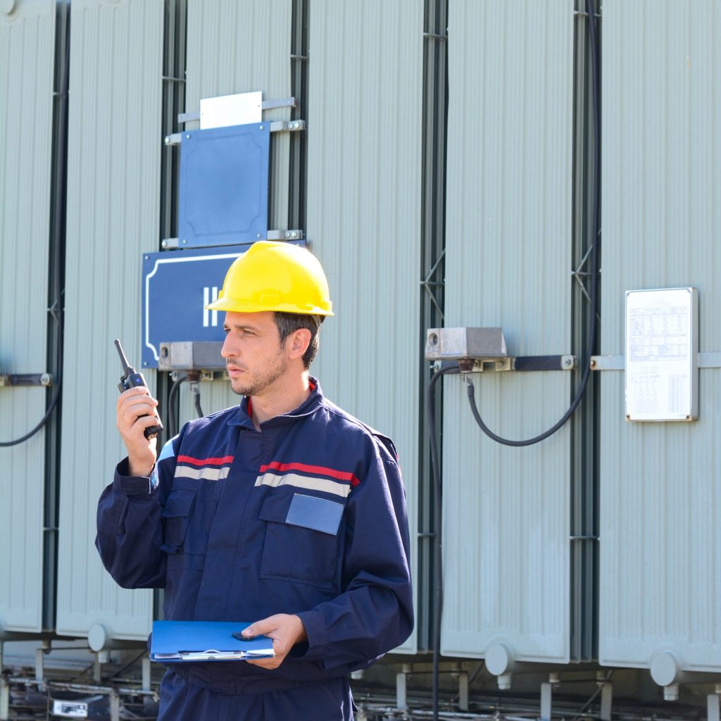 Electrician working in power plant. Man at work with Walkie Talkie and ring binder in his hand.