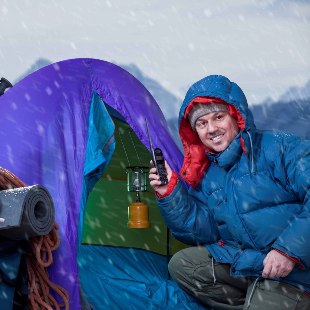 Mountaineer and Blue expedition tent in front of mountain range. Background to the Himalayas.