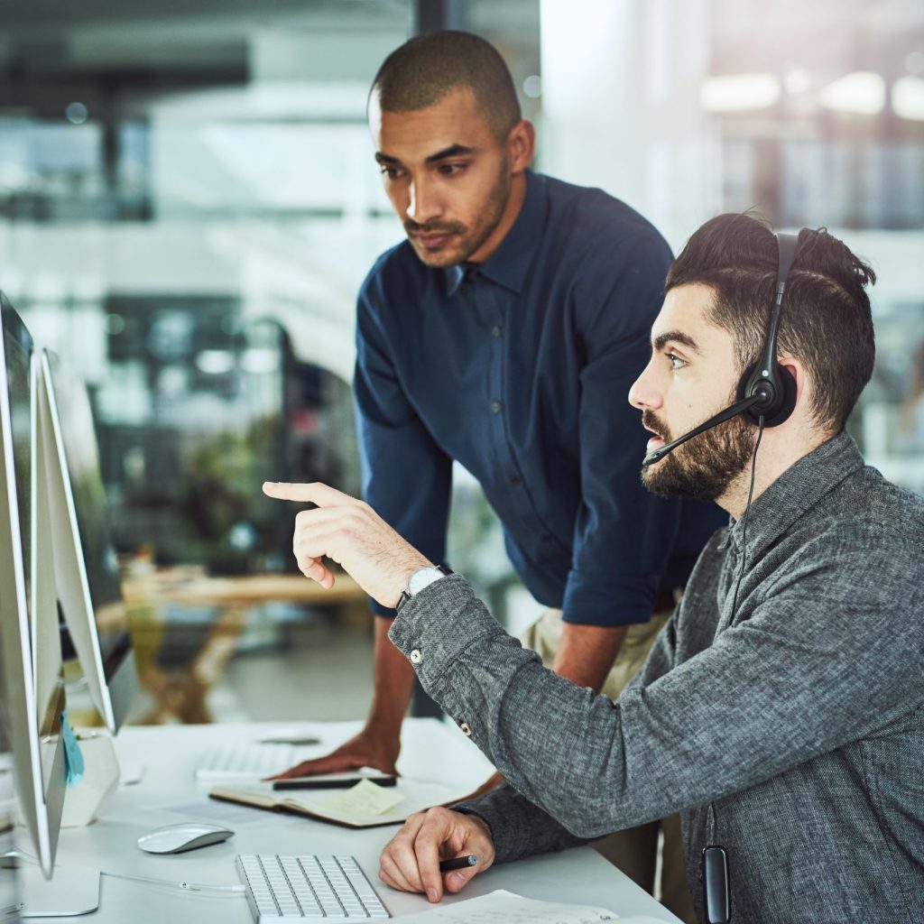 Shot of a young businessman assisting a colleague in a call centre