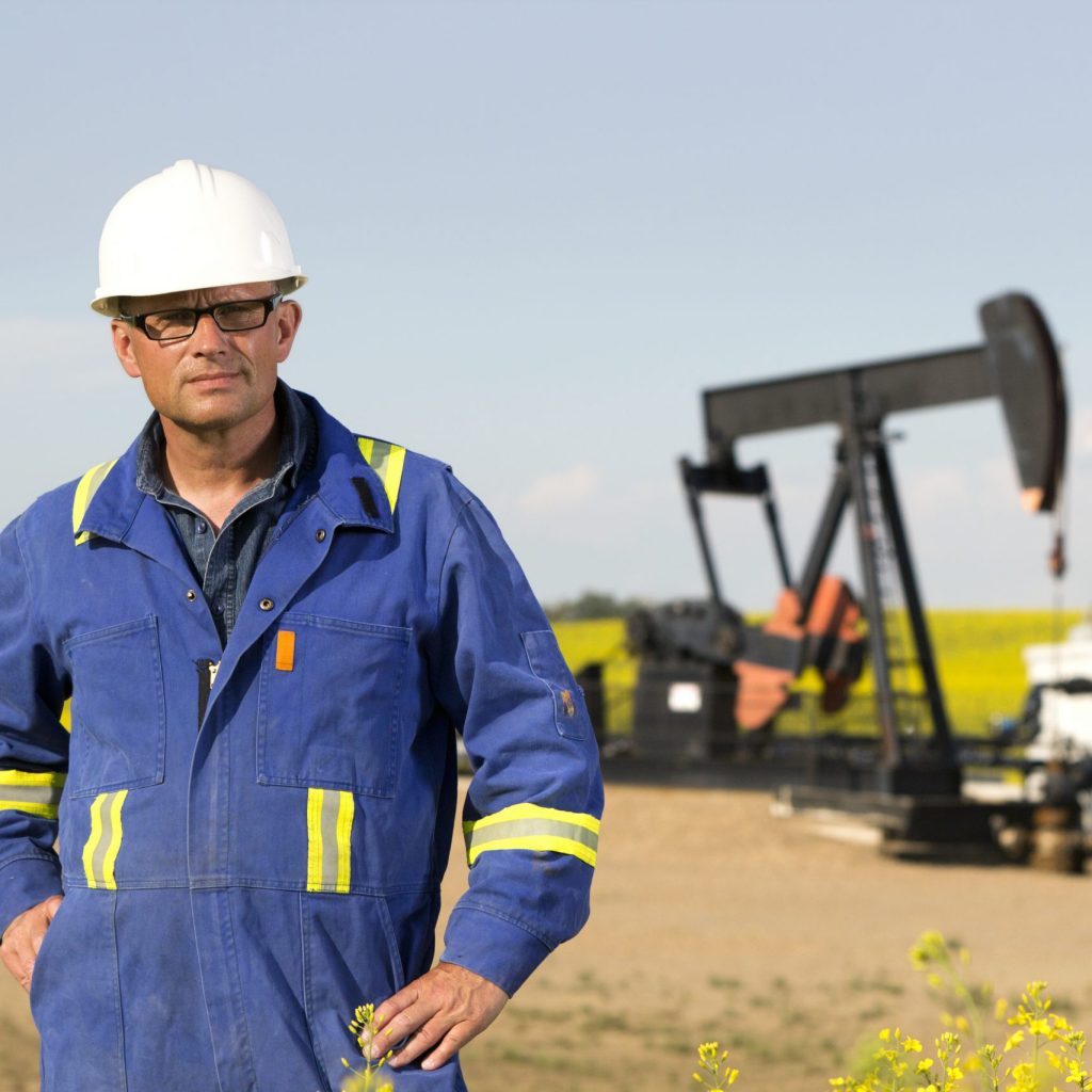 wearable tablet technology in alberta A royalty free image from the oil and gas industry of an engineer standing in front of oil equipment.